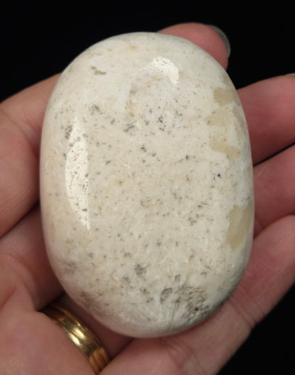 white crystal palm carving being held in a hand against a black background