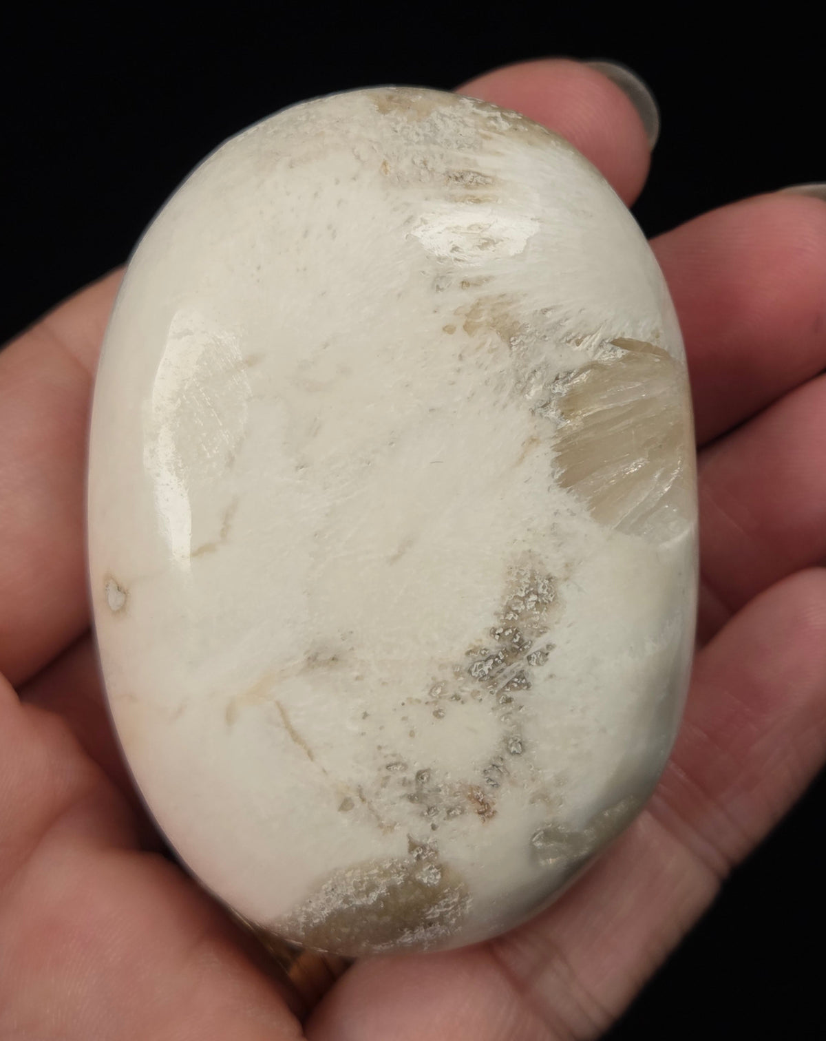 white crystal palm carving being held in a hand against a black background