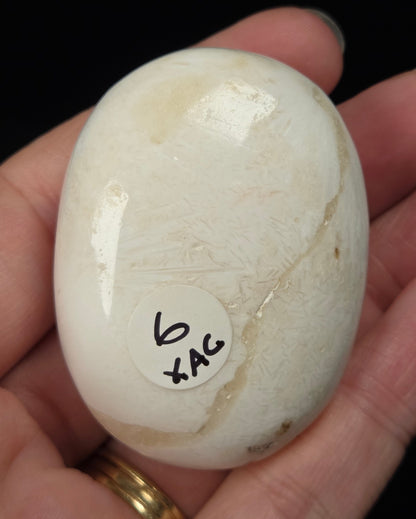 white crystal palm carving being held in a hand against a black background