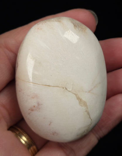 white crystal palm carving being held in a hand against a black background