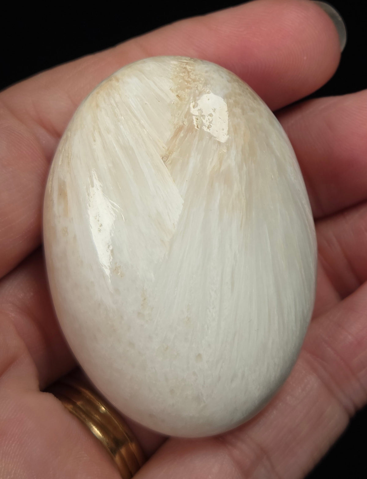 white crystal palm carving being held in a hand against a black background