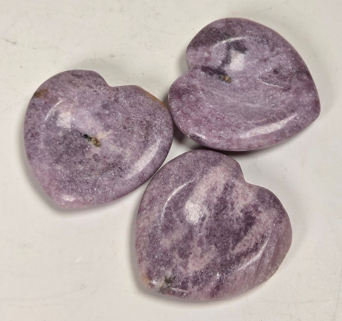 heart shaped lepidolite crystal carvings against a white background