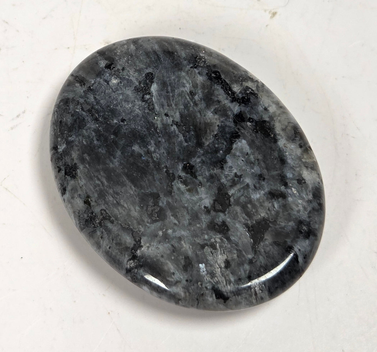 black and yellow larvakite crystal carving against a white background
