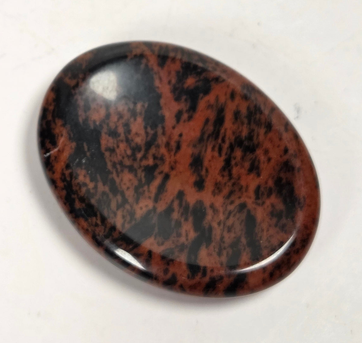 mahogany obsidian crystal carving against a white background
