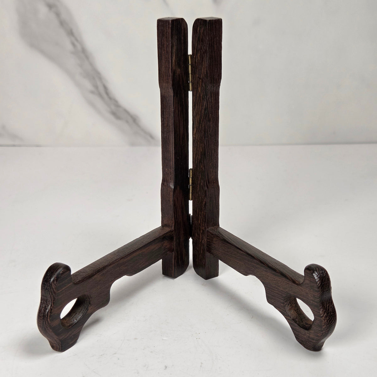 Dark wooden stand on a white surface with a marble-patterned wall in the background