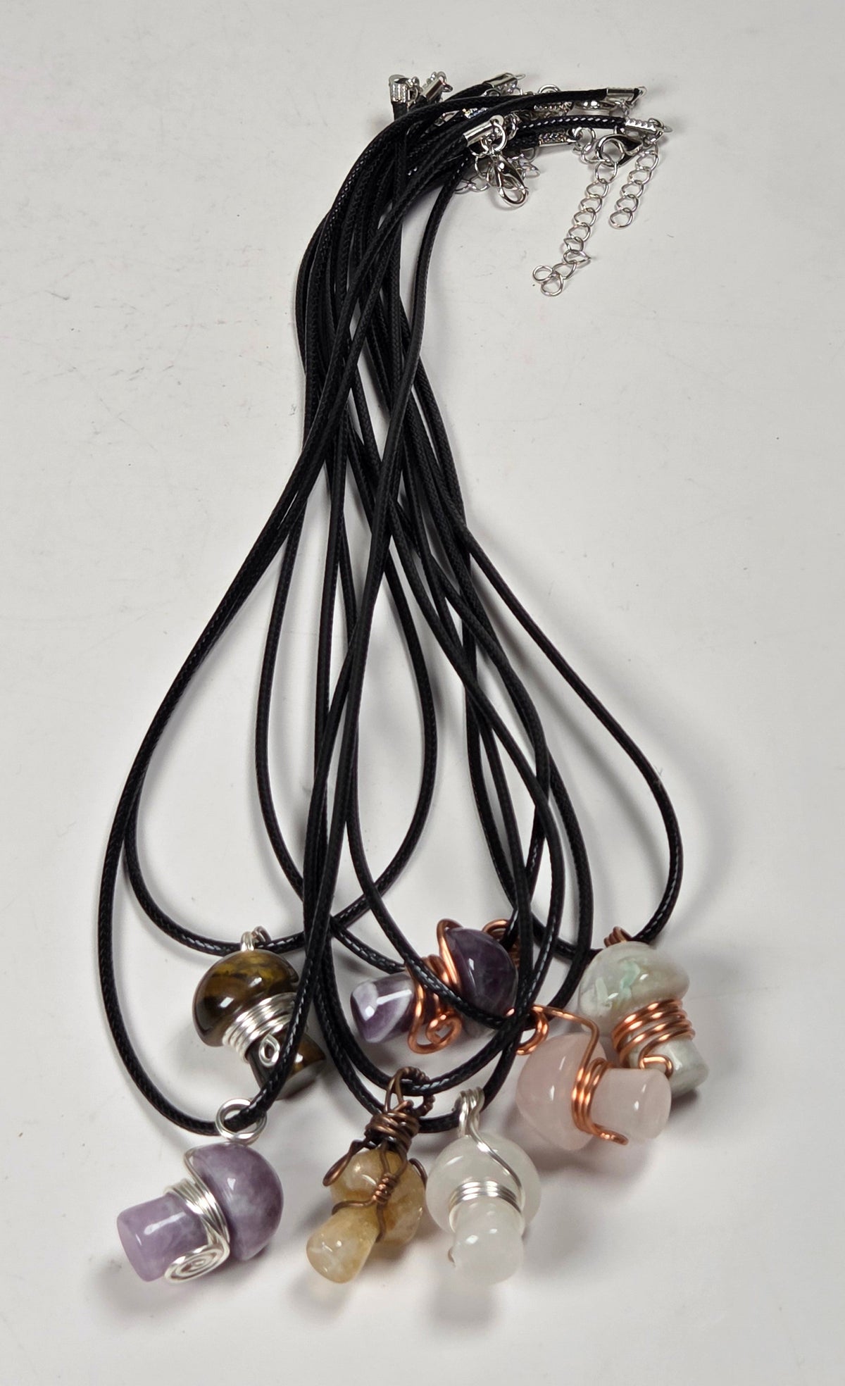 collection of mushroom shaped necklaces on black cords against a white background