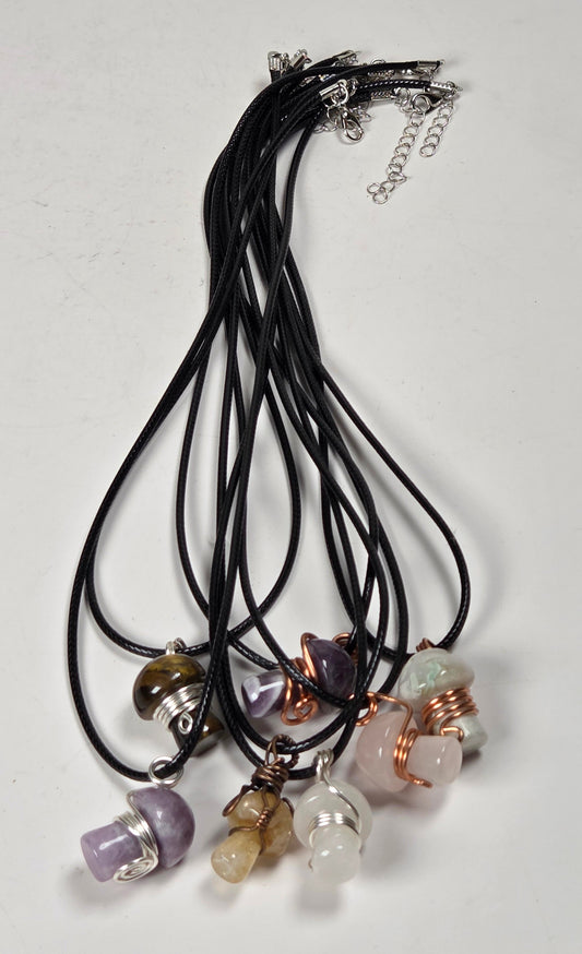 collection of mushroom shaped necklaces on black cords against a white background
