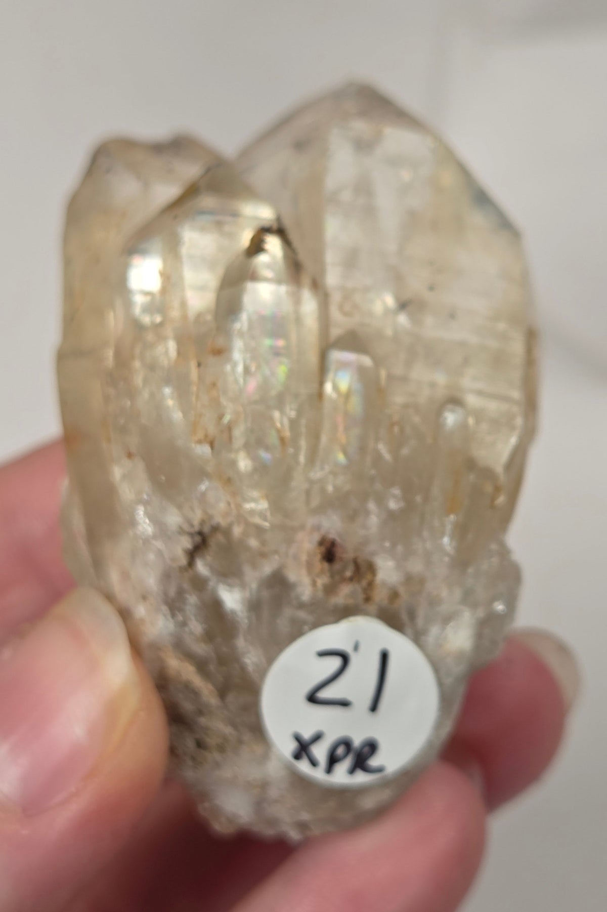 citrine cluster specimen being held in a hand  against a white marbled background