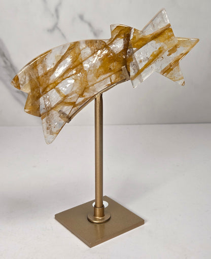 crystal shooting star carving in a gold stand against a marbled white background