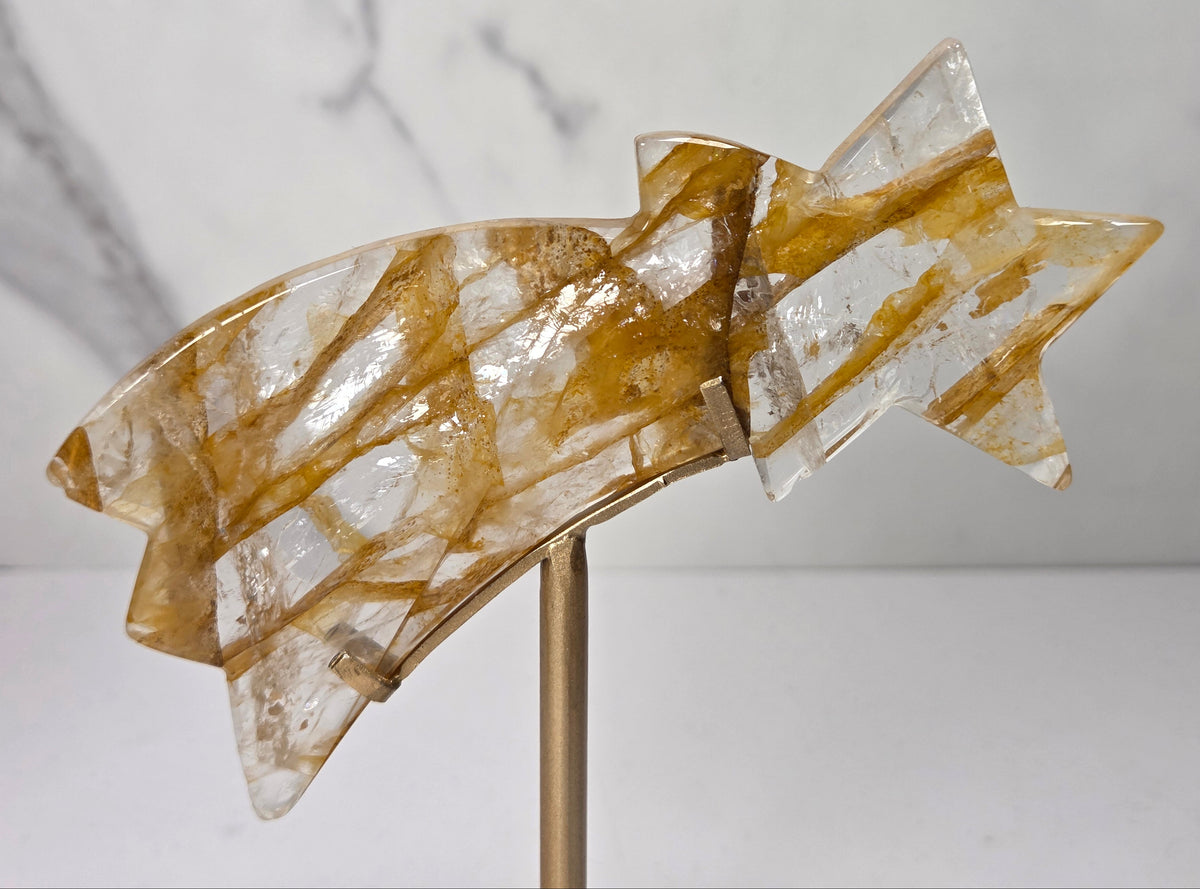 crystal shooting star carving in a gold stand against a marbled white background
