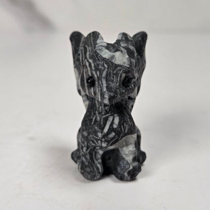 A small carved figurine of a dragon or fantasy creature made from black and white marbled stone, standing on a light surface with a soft blurred background.