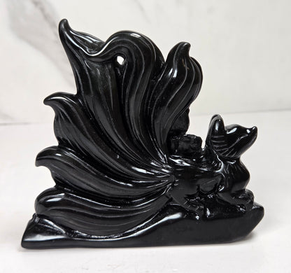 Obsidian stylized fox carving against a white marbled background.