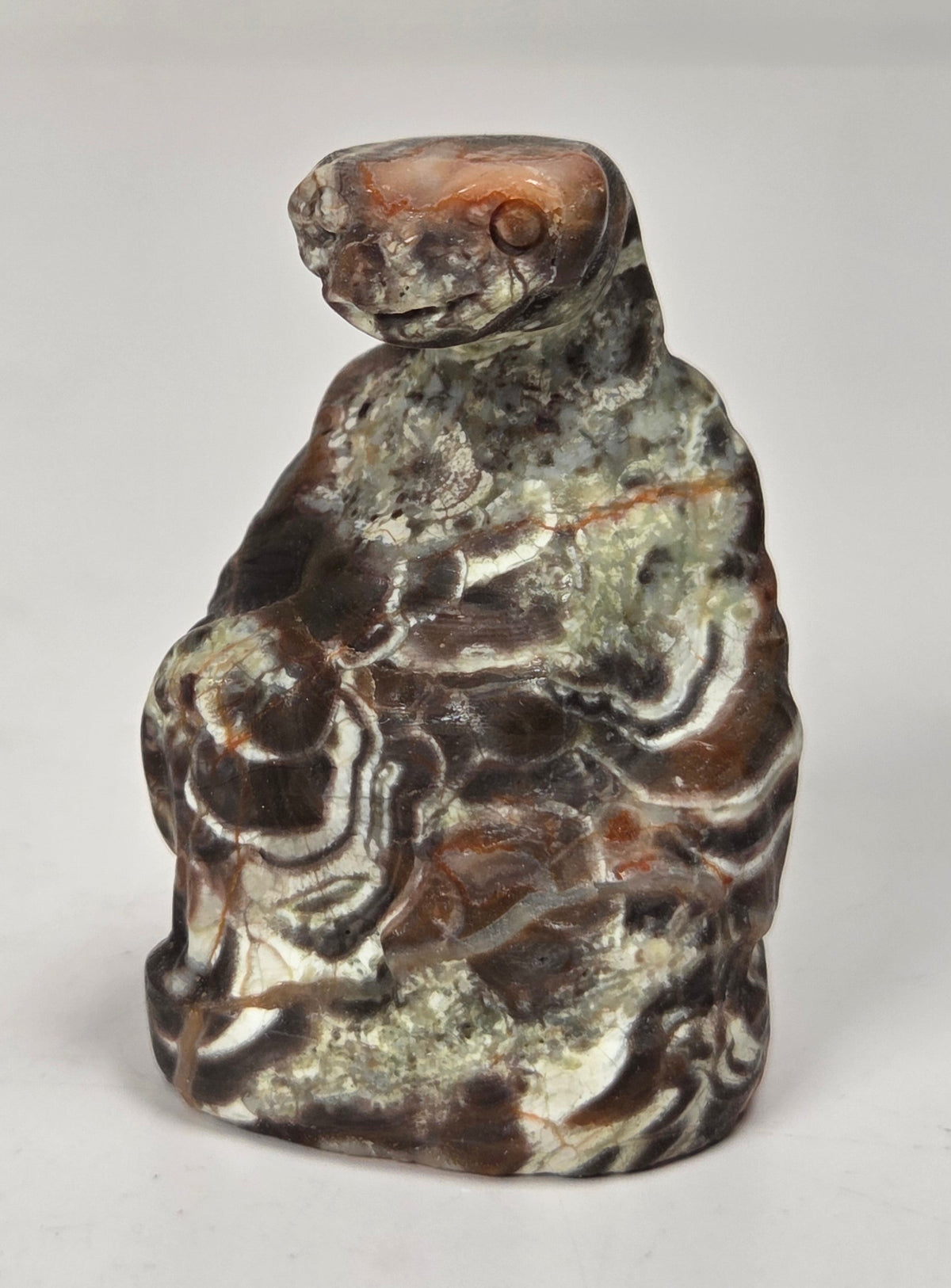 A small carved figurine of a seated rabbit made from patterned stone with brown, gray, and white marbled swirls, photographed on a plain light background.