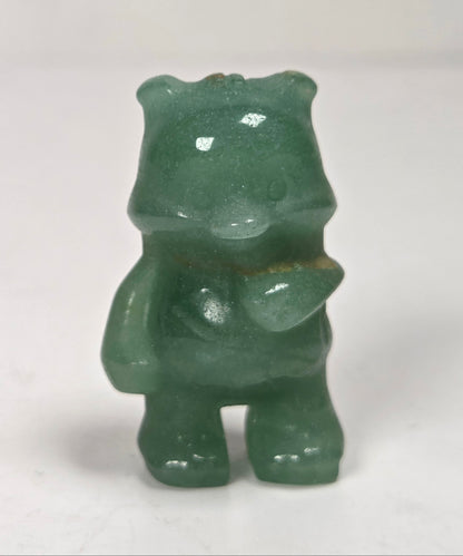 A small green translucent figurine of a bear-like character standing on a white surface against a white background.
