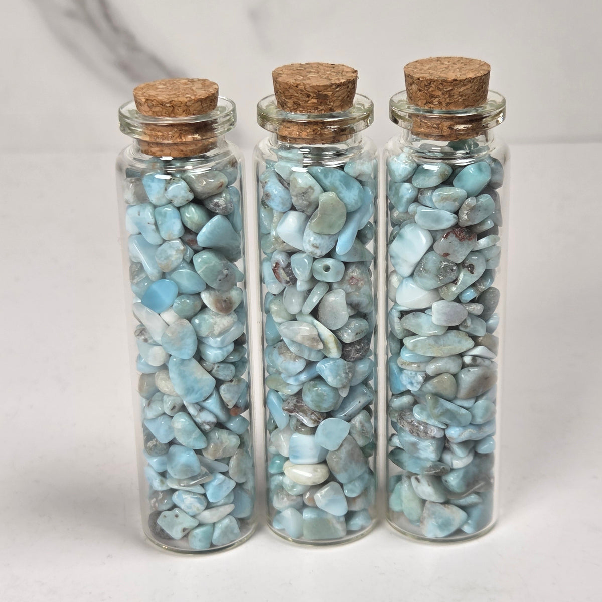 blue and white crystal chip in glass bottles with cork tops against a marbled background