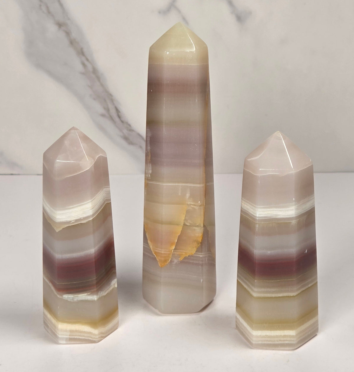 Banded calcite carved points with tan, pink, white and light green coloring against a marbled background