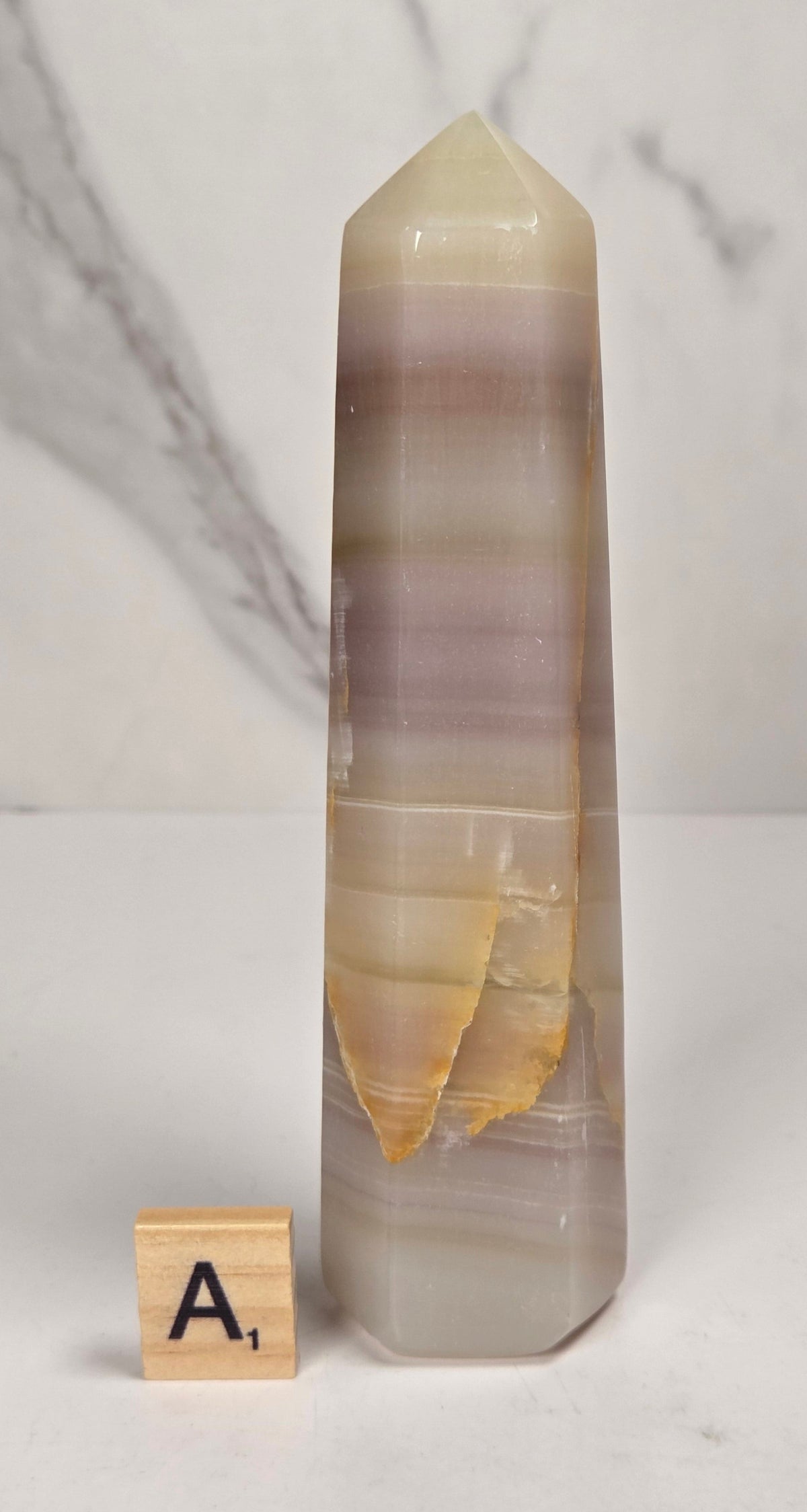 Banded calcite carved points with tan, pink, white and light green coloring against a marbled background