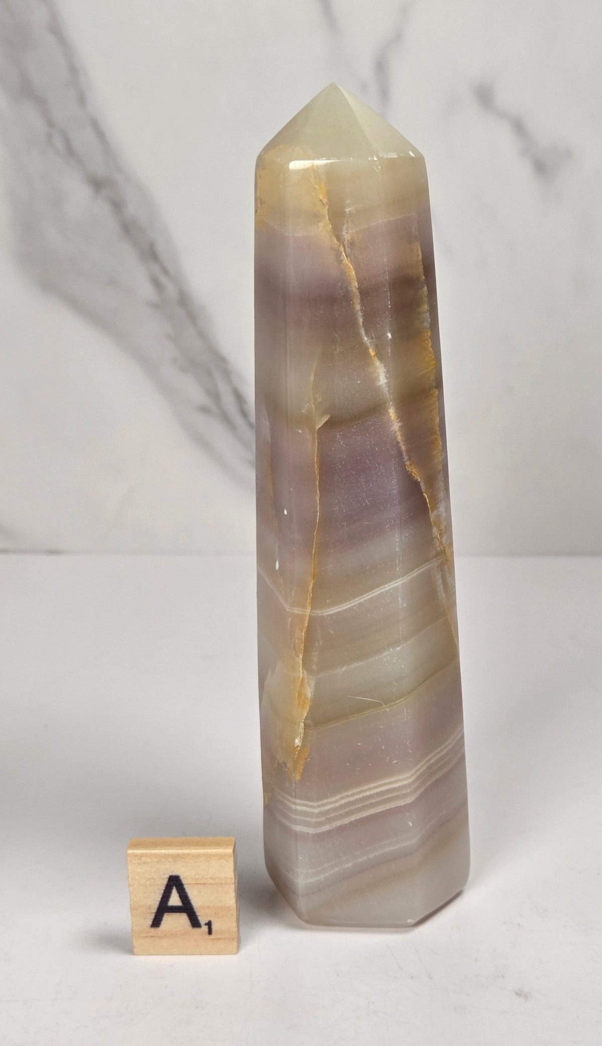 Banded calcite carved points with tan, pink, white and light green coloring against a marbled background