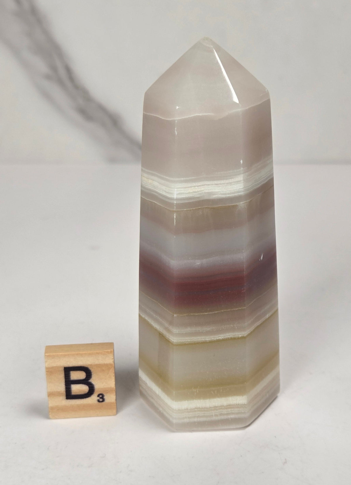 Banded calcite carved points with tan, pink, white and light green coloring against a marbled background