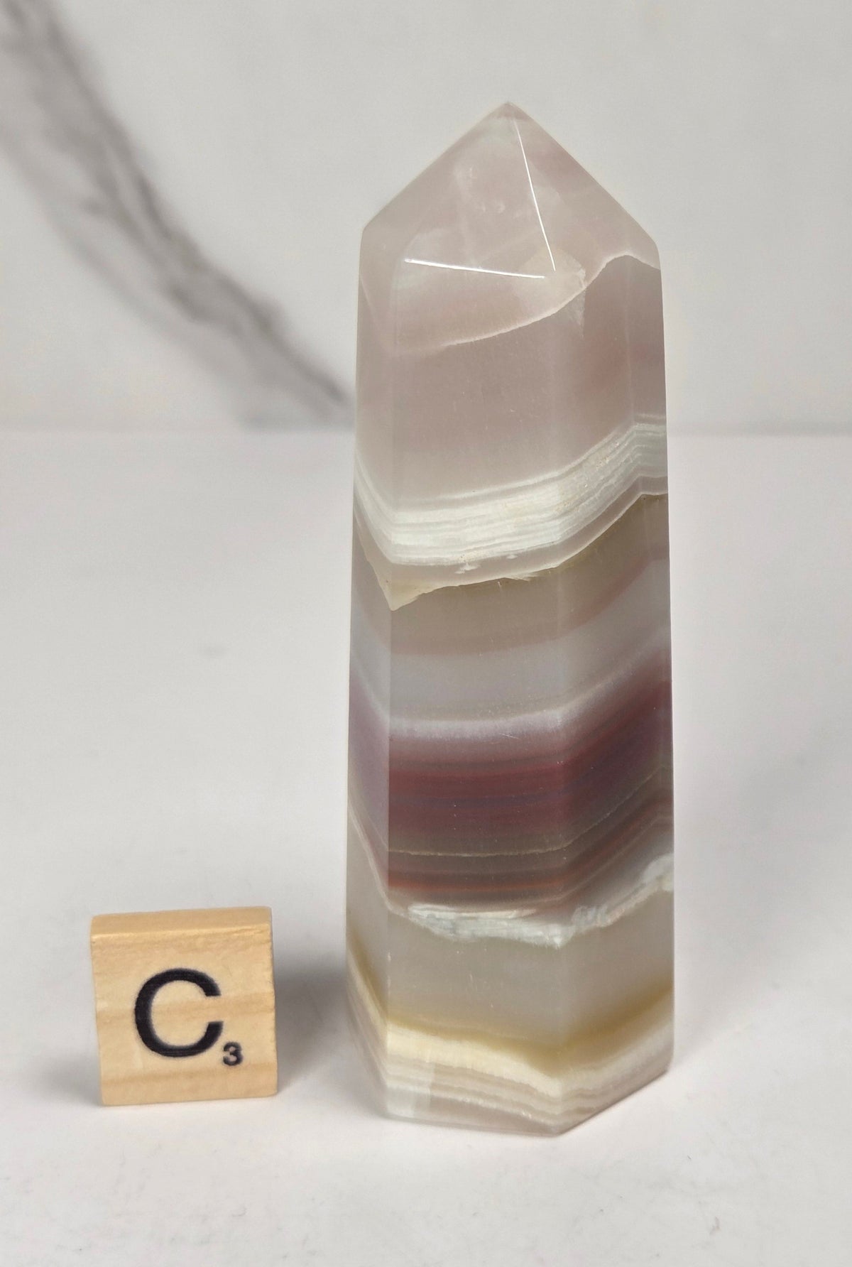 Banded calcite carved points with tan, pink, white and light green coloring against a marbled background