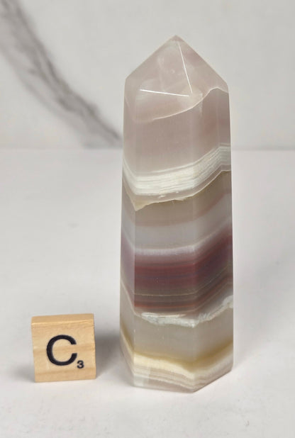 Banded calcite carved points with tan, pink, white and light green coloring against a marbled background