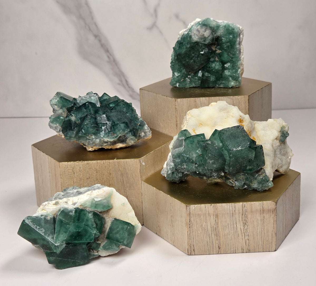 Green Fluorite specimens on white matrix on a wooded stand against a marbled background