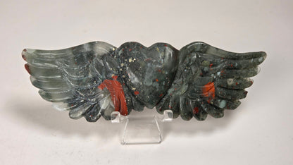 Crystal heart with wings carving with black, grey, red and gold coloring on an acrylic chair against a white background