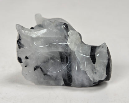 A small dragon head sculptures made of Quartz with black tourmaline inclusions on a white background