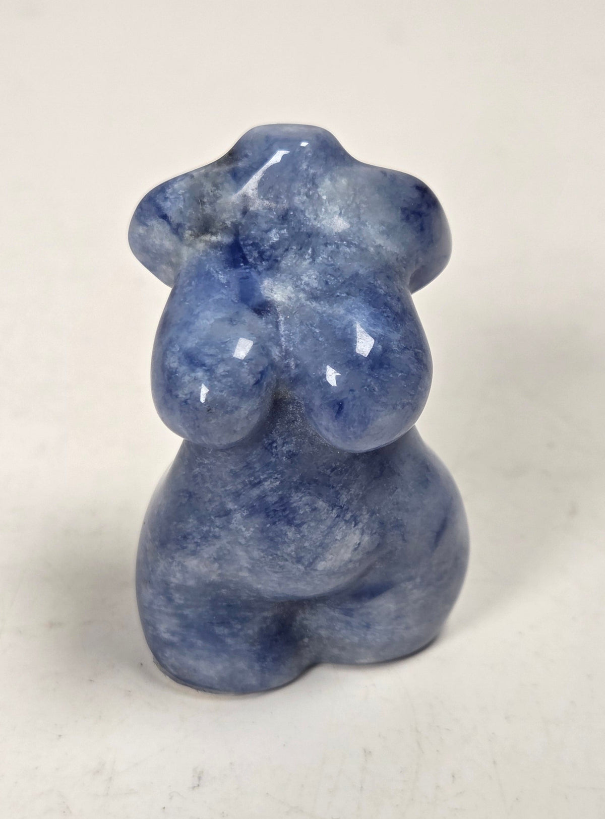 Sculpture of a goddess body made of Sodalite displayed on a white background