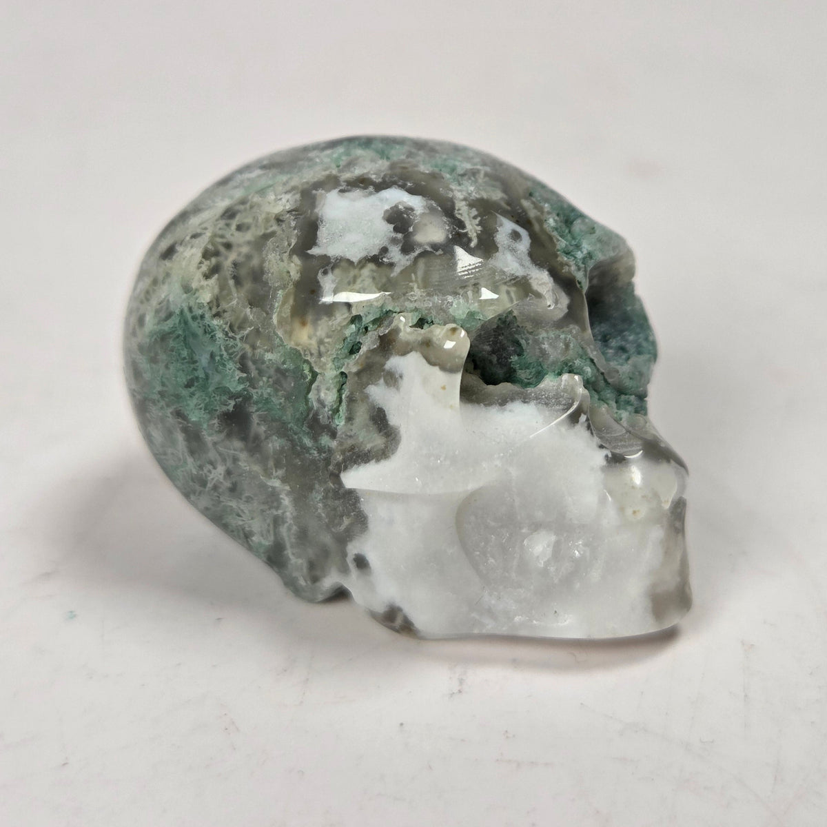 moss agate skull carving against a white background
