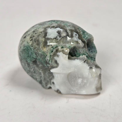 moss agate skull carving against a white background