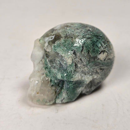 moss agate skull carving against a white background