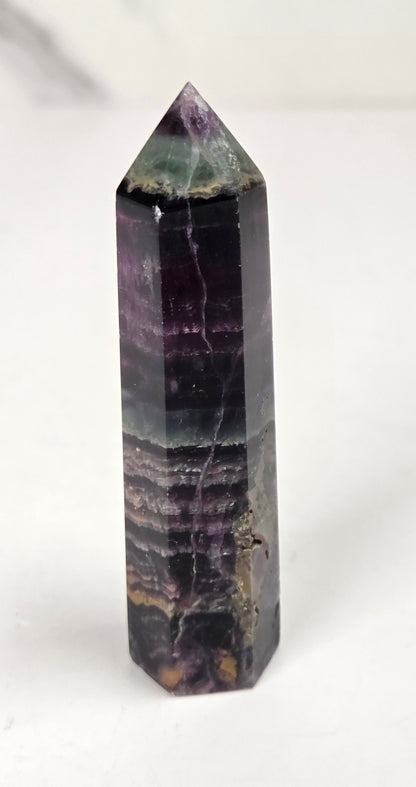 colorful banded fluorite tower with green and purple coloring against a white background