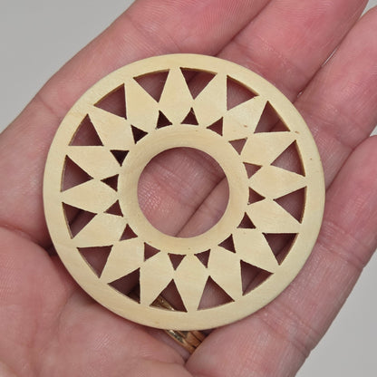hand holding a starburst style wood circle on a white background
