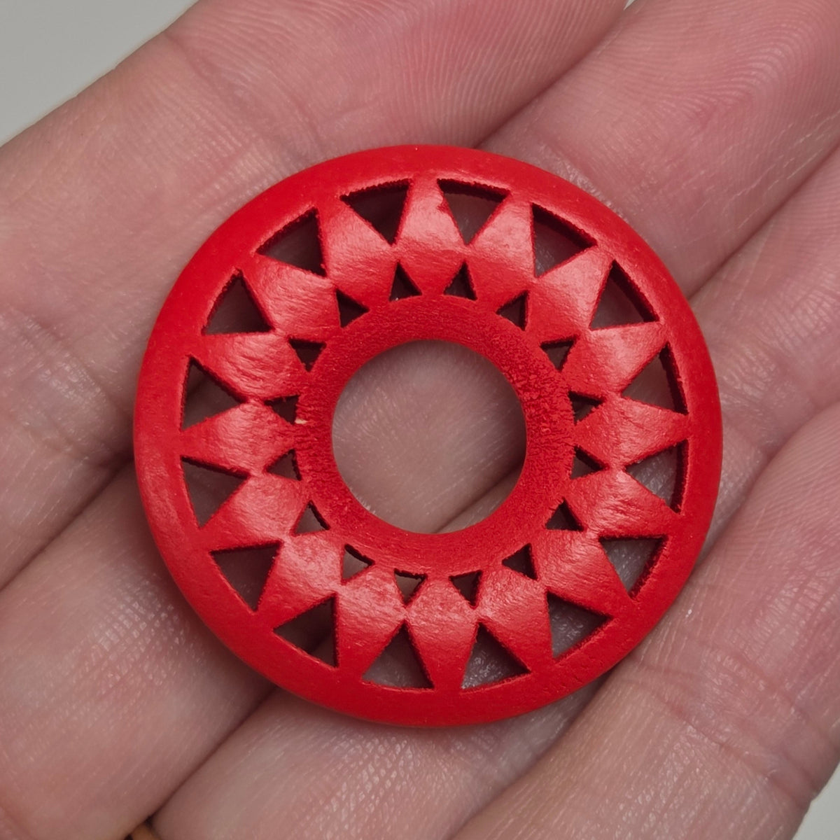 hand holding a starburst style wood circle on a white background