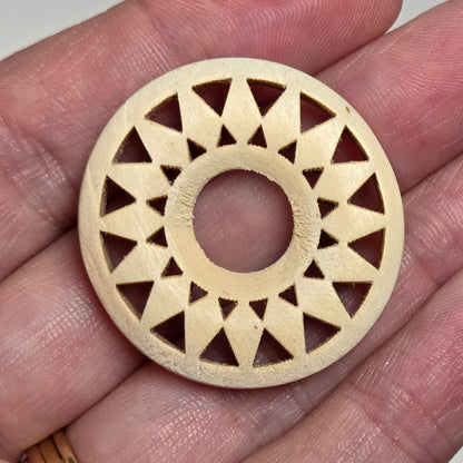 hand holding a starburst style wood circle on a white background