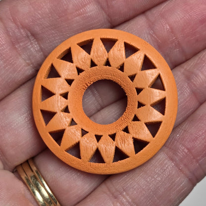 hand holding a starburst style wood circle on a white background