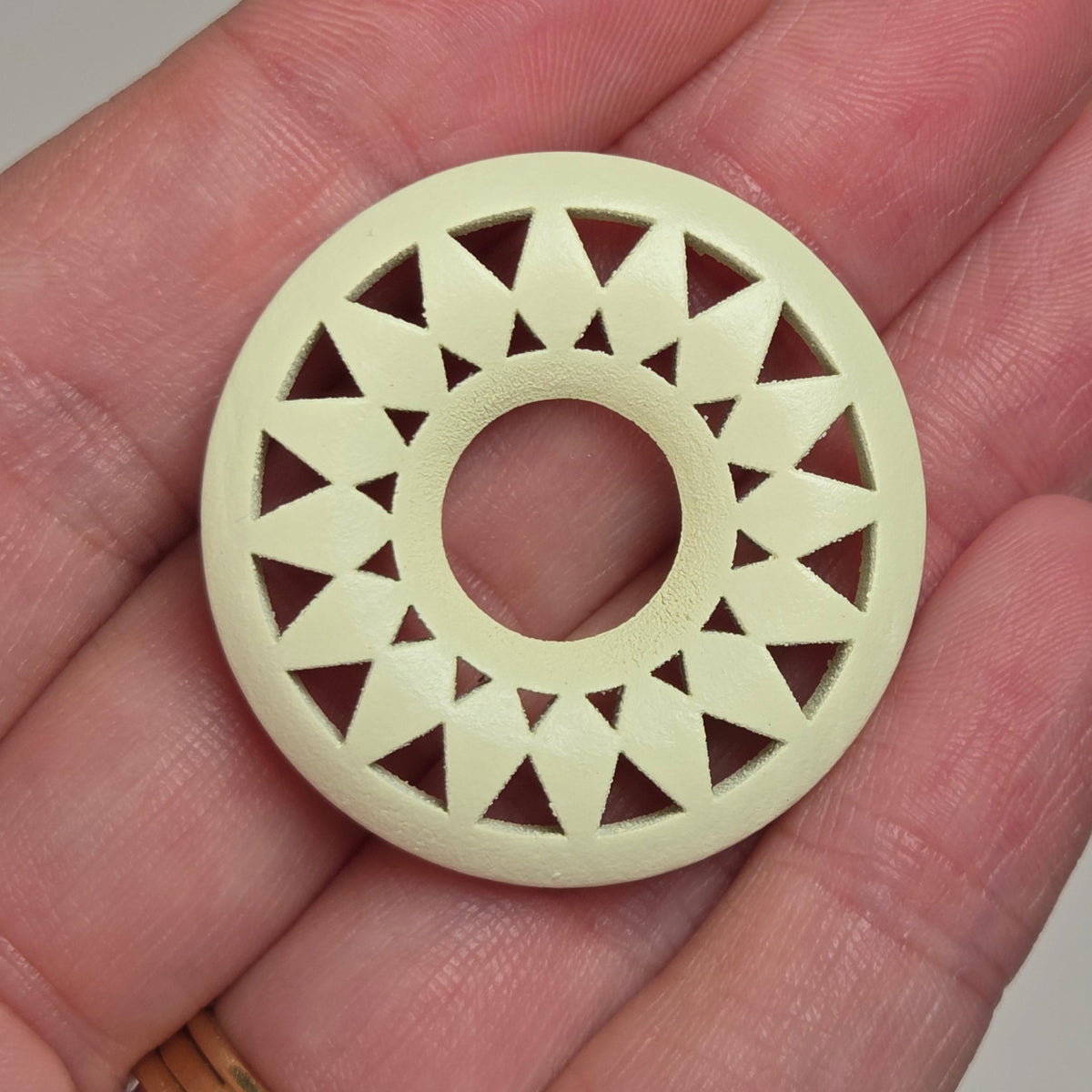 hand holding a starburst style wood circle on a white background