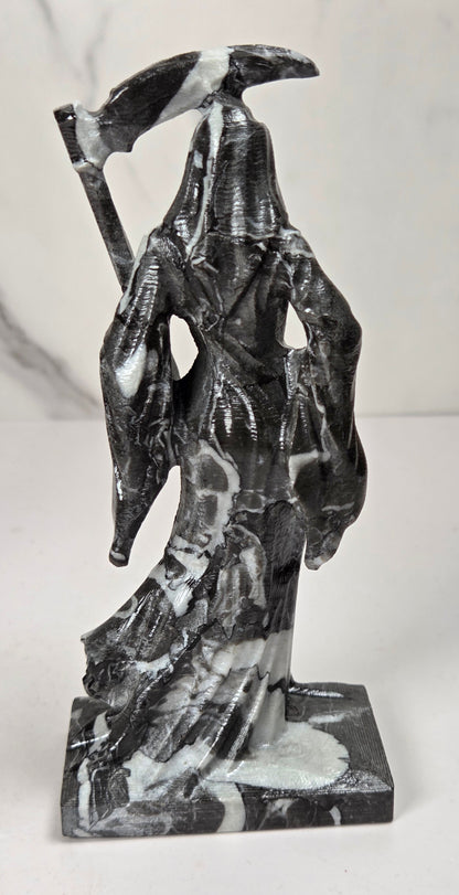 faceless lady reaper carving made of a  marbled black and white mineral against a marbled white background