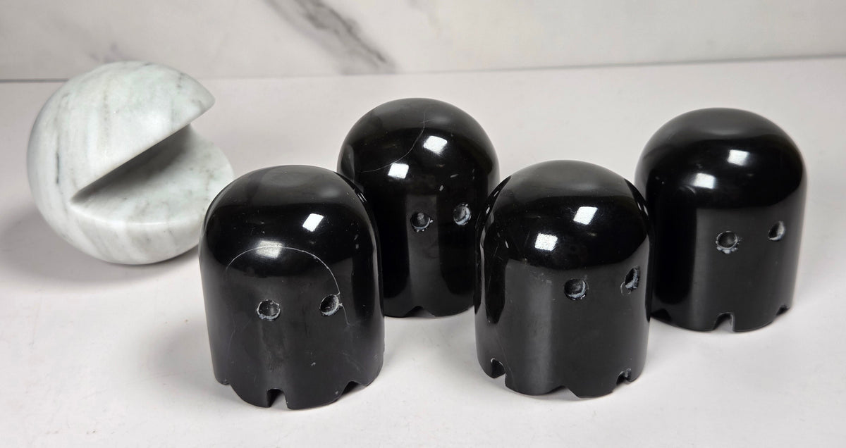 marble carvings of a white pac-man and 4 black ghosts against a marbled background