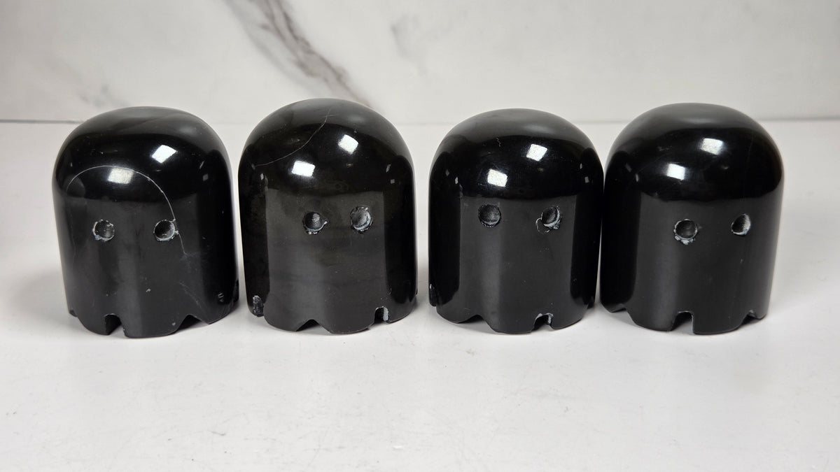 marble carvings of 4 black ghosts against a marbled background