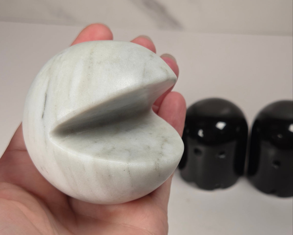 marble carvings of a white pac-man and 4 black ghosts against a marbled background