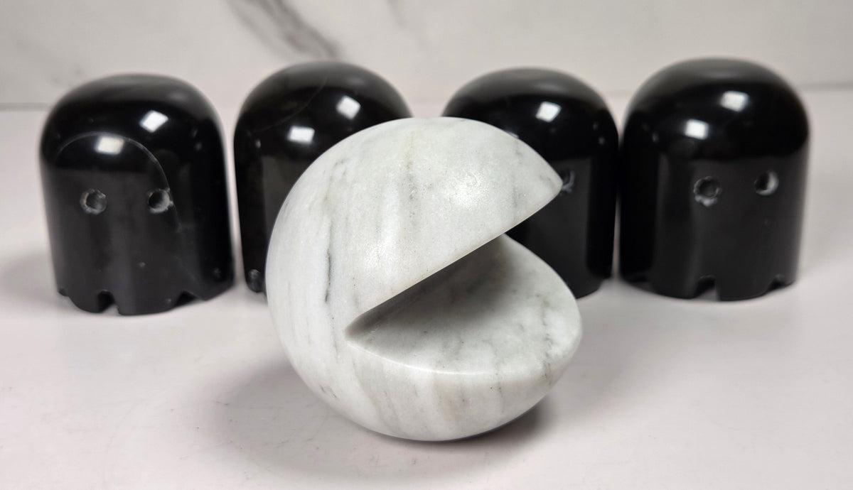marble carvings of a white pac-man and 4 black ghosts against a marbled background