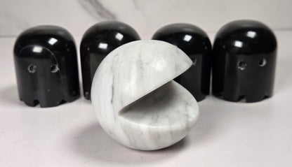 marble carvings of a white pac-man and 4 black ghosts against a marbled background
