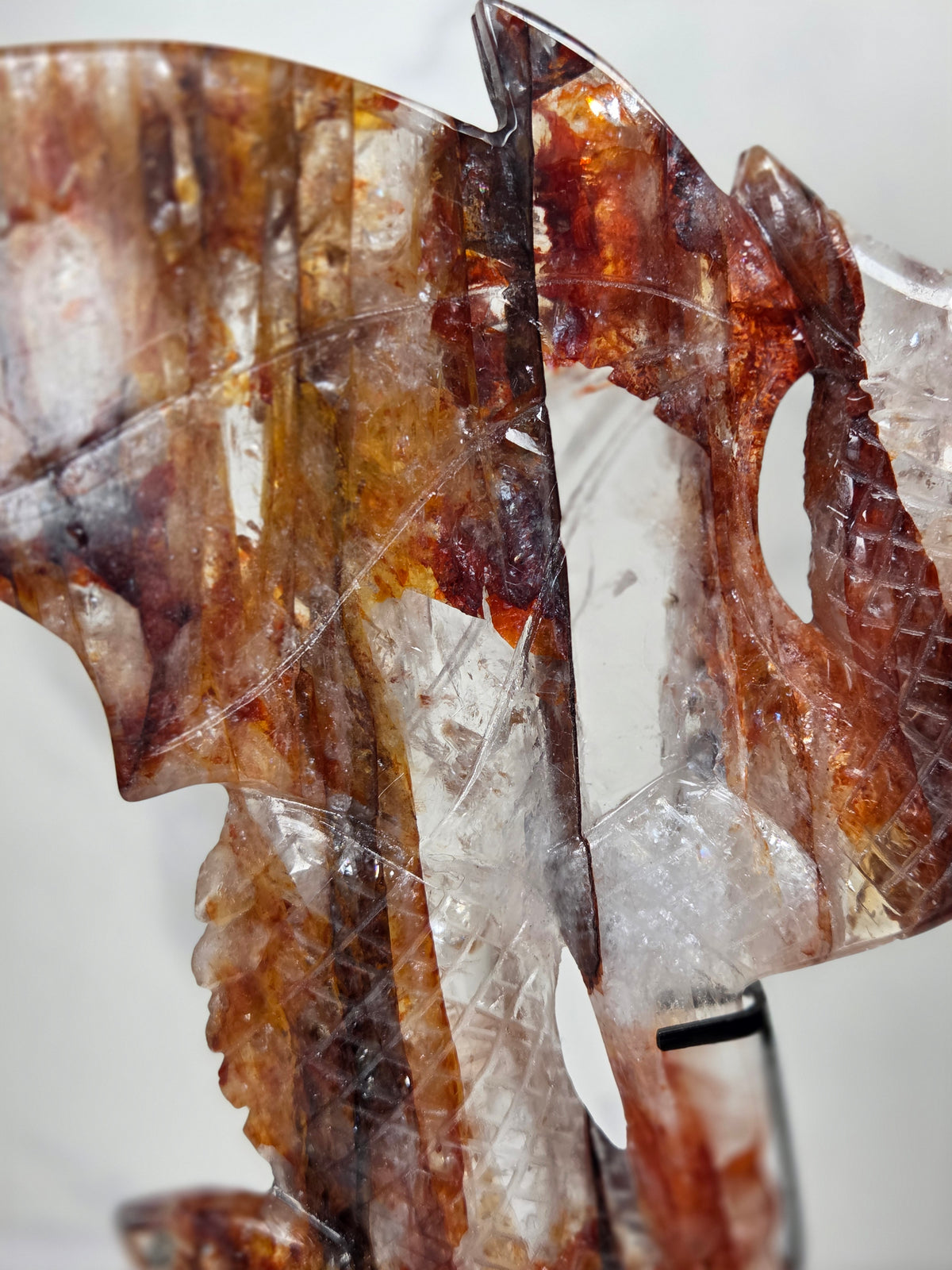 Close-up of a Quartz dragon carving with red and orange inclusions against a marbled background