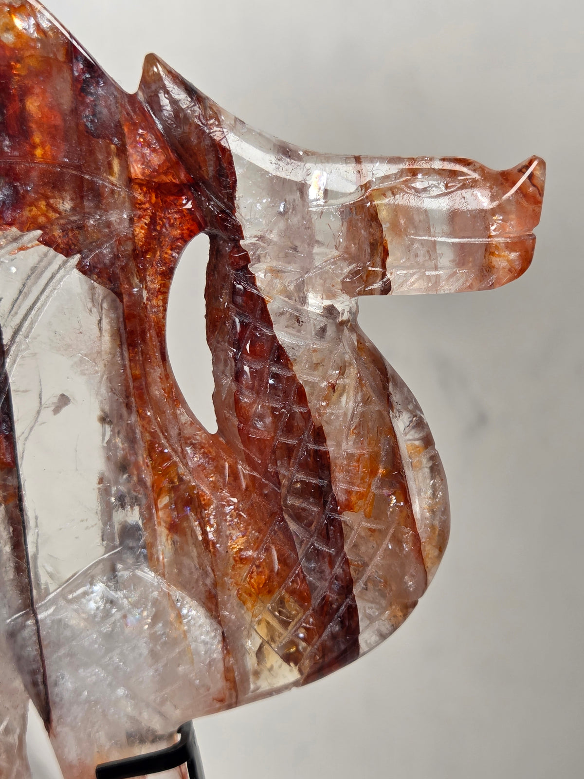 Close-up of a Quartz dragon carving with red and orange inclusions against a marbled background