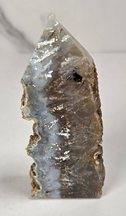 Close-up of a crystal point with inclusions against a white background