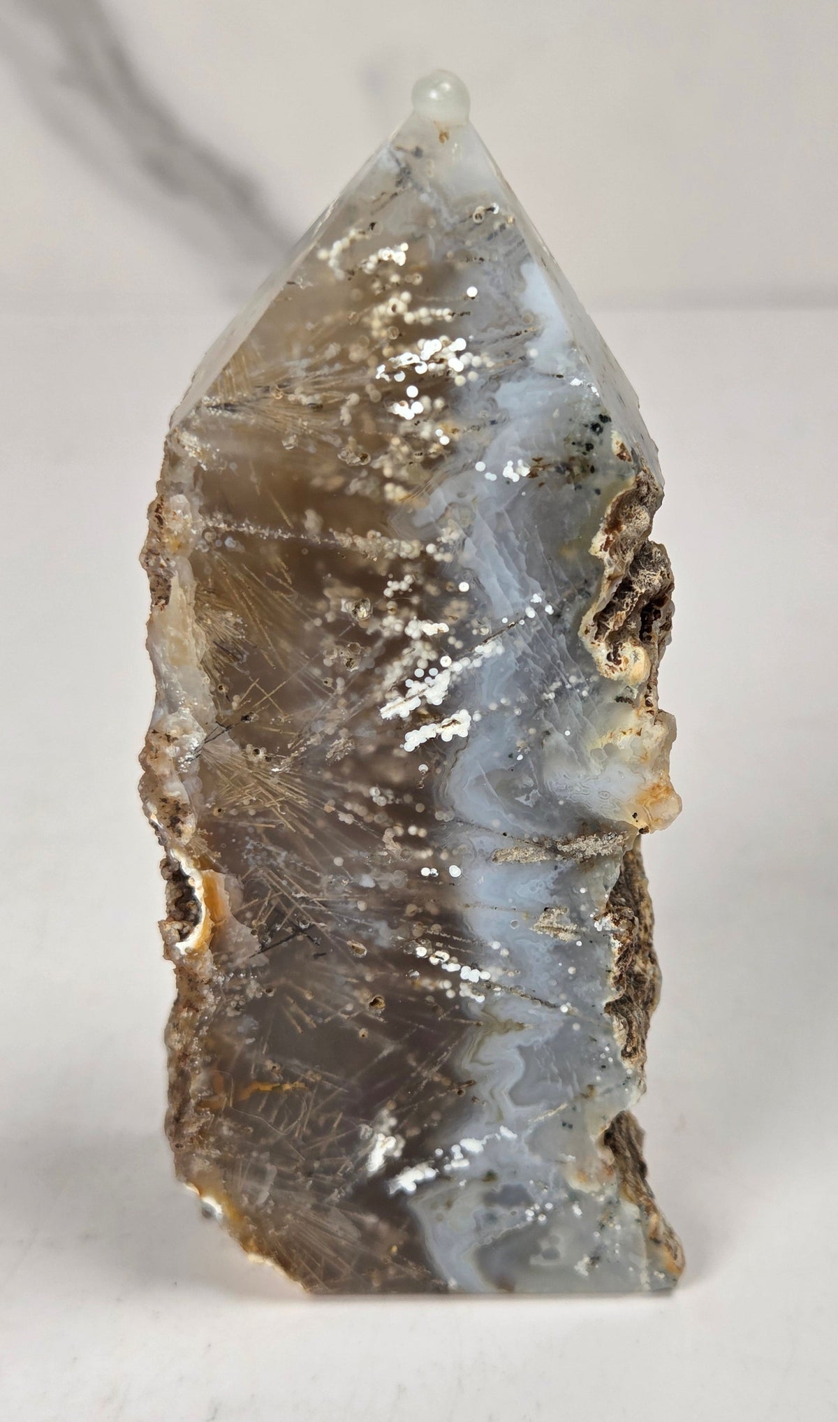 Close-up of a crystal point with inclusions against a white background