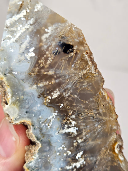 Close-up of a crystal point with inclusions against a white background