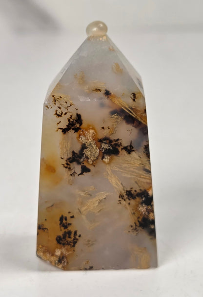 Close-up of a crystal point with inclusions against a white background
